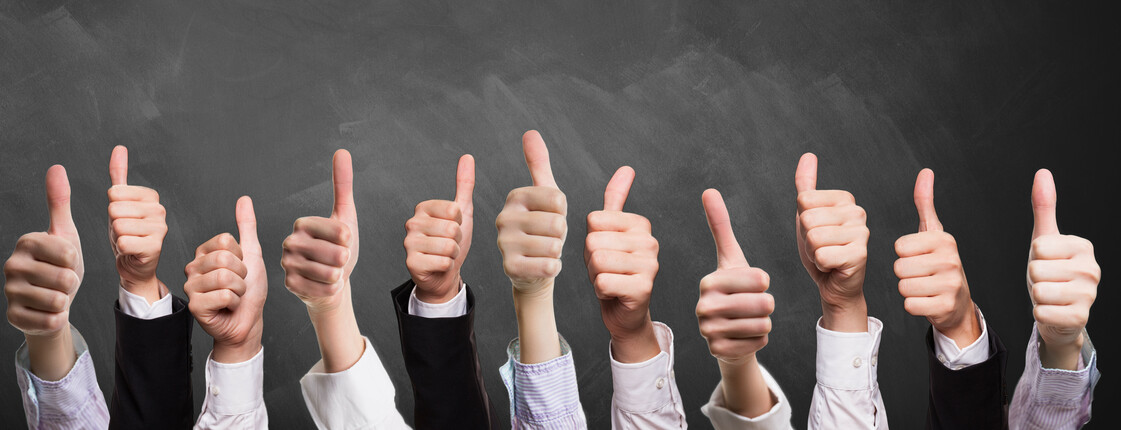 many thumbs up in front of a blackboard