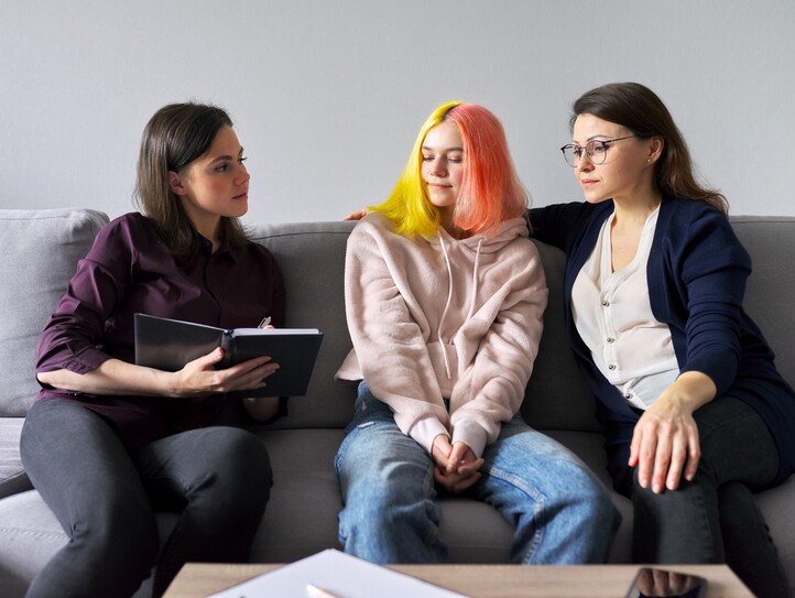 Woman social worker talking to mother and daughter teenage girl